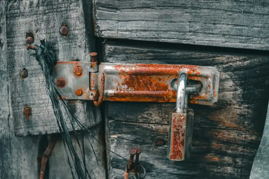 Close-up of a rusty padlock on an old wooden door, showing texture and decay.