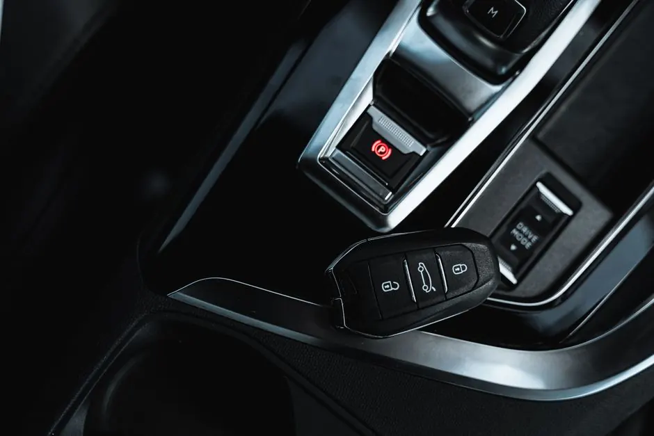 Close-up view of a keyless fob and electronic handbrake in a modern car interior.