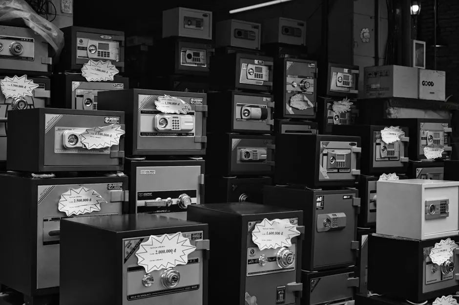 Monochrome photo of stacked safes with price tags in a store setting.