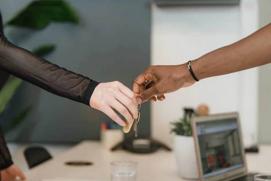 Professional office setting showing a key exchange symbolizing a business deal or real estate transaction.