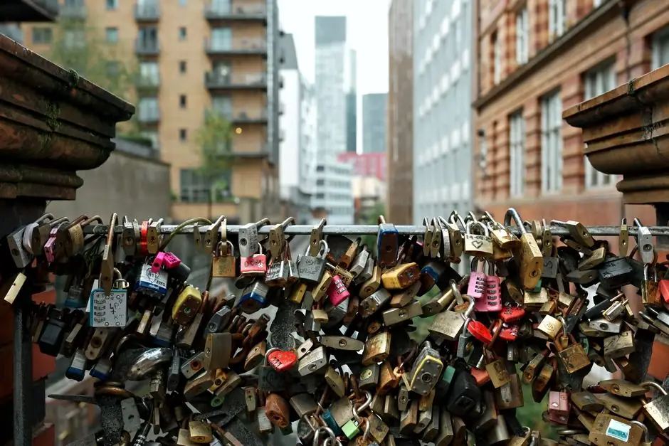 This image captures an urban bridge filled with symbolic love locks against a city backdrop.